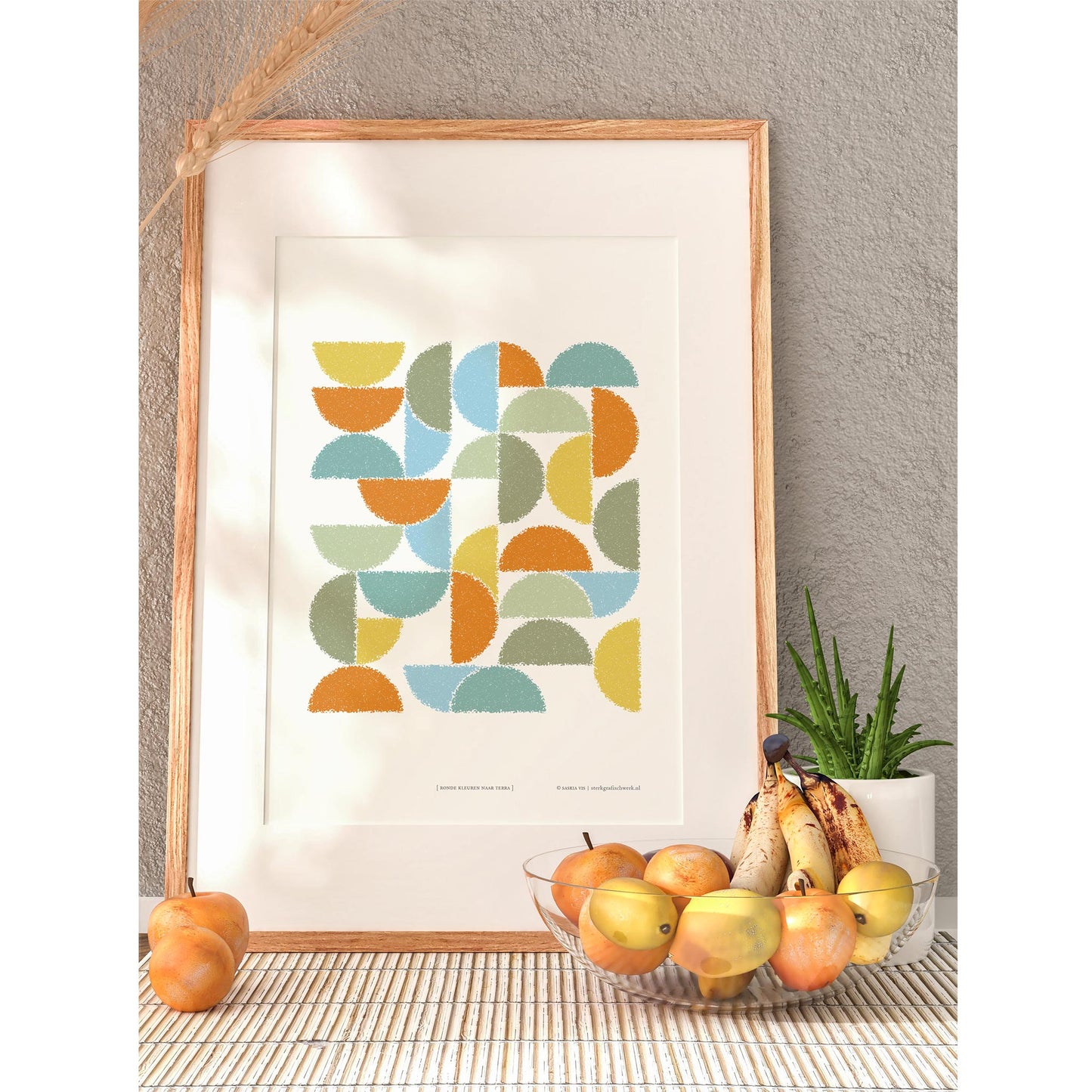 Productafbeelding, poster "ronde kleuren naar terra", in een houten lijst met een schaal en wat fruit erbij, ter impressie