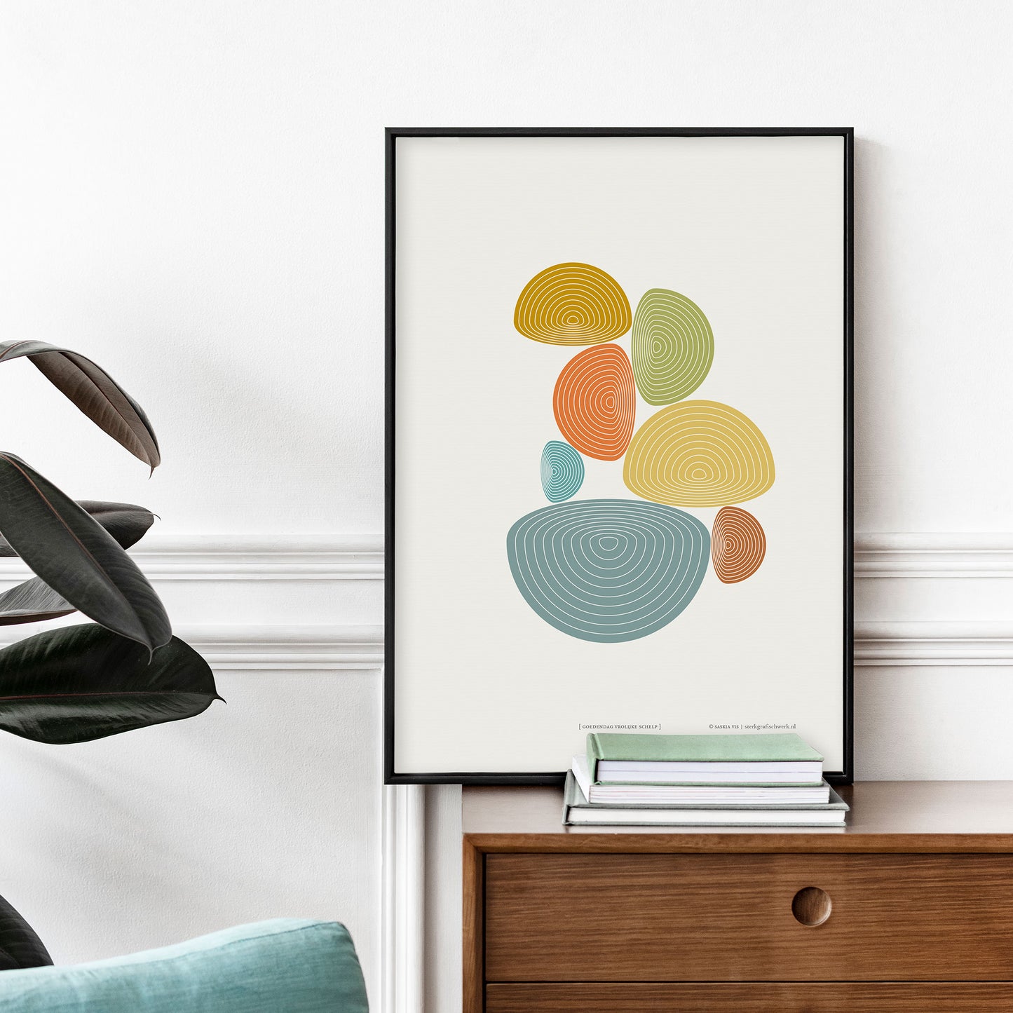 Productafbeelding, poster "goedendag vrolijke schelp", in een zwarte lijst staande op een houten meubel tegen een decoratieve wand