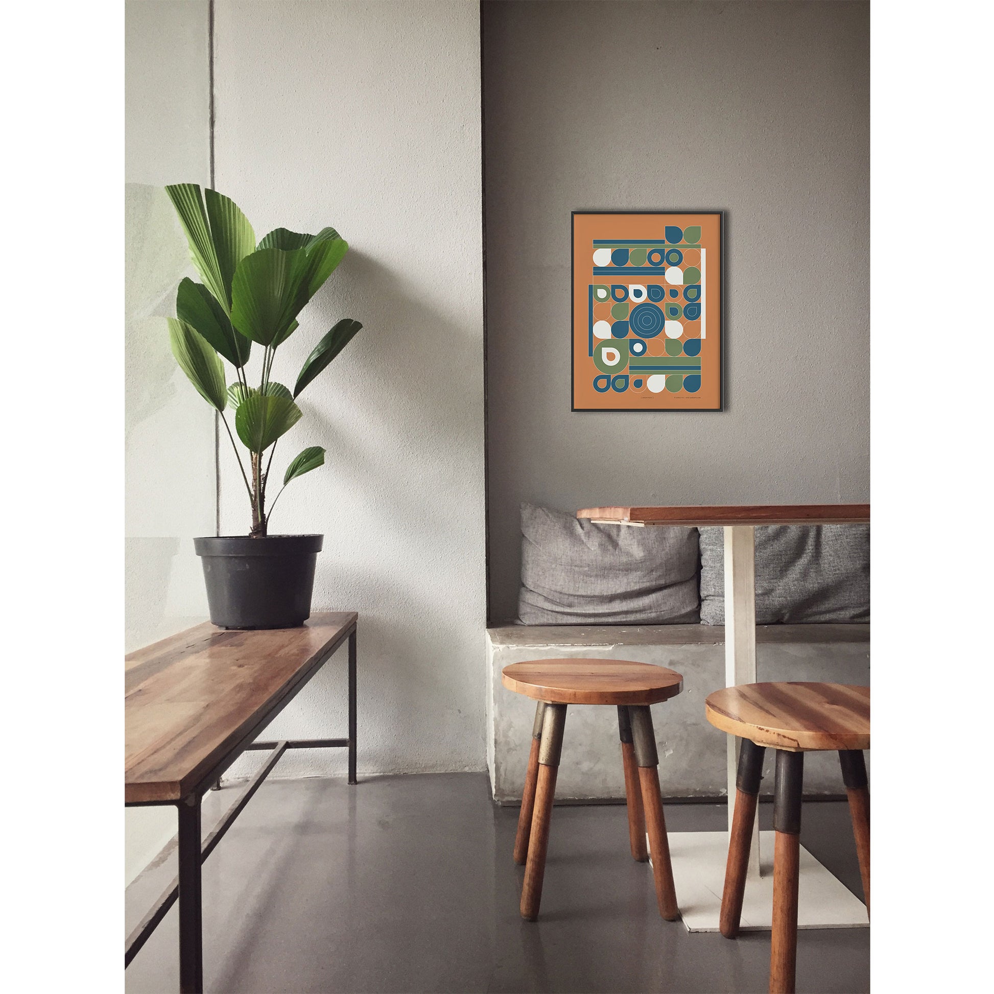 Productafbeelding, poster "jardin jaune", foto impressie 1, ingelijst hangend boven een tafel aan een wand, in een interieur met een plant en krukjes
