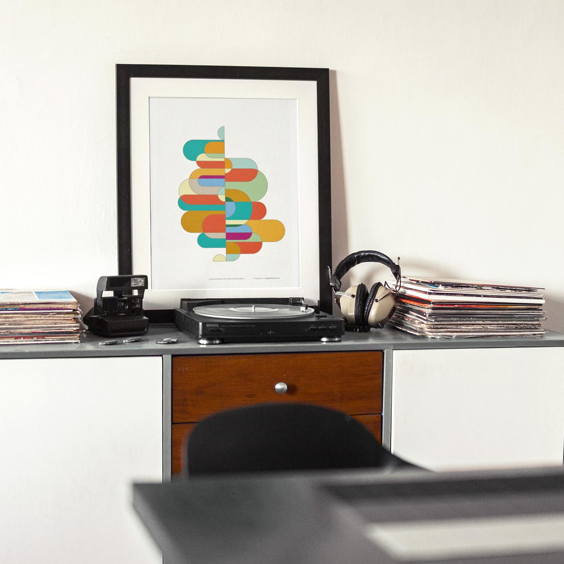 Productafbeelding, poster "kleur-acrobaat met ronde rechthoeken", foto impressie 3, staande op een tafel in een interier met een 'draaitafel' erbij