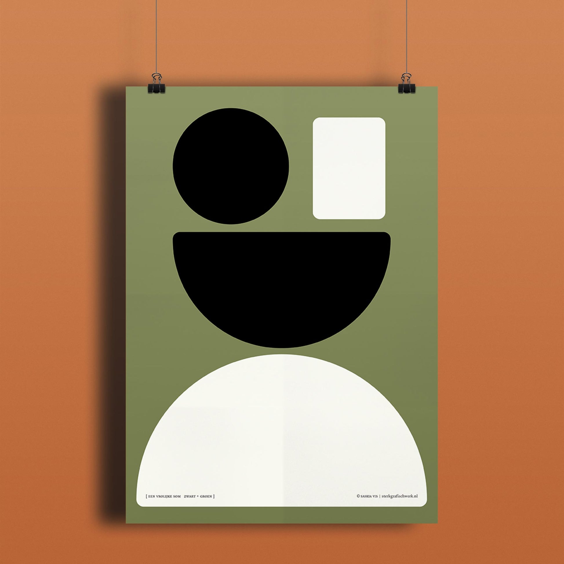 Productafbeelding, poster "een vrolijke som zwart+groen", hangend aan een donker oranje/bruin gekleurde wand, een overzichtsfoto