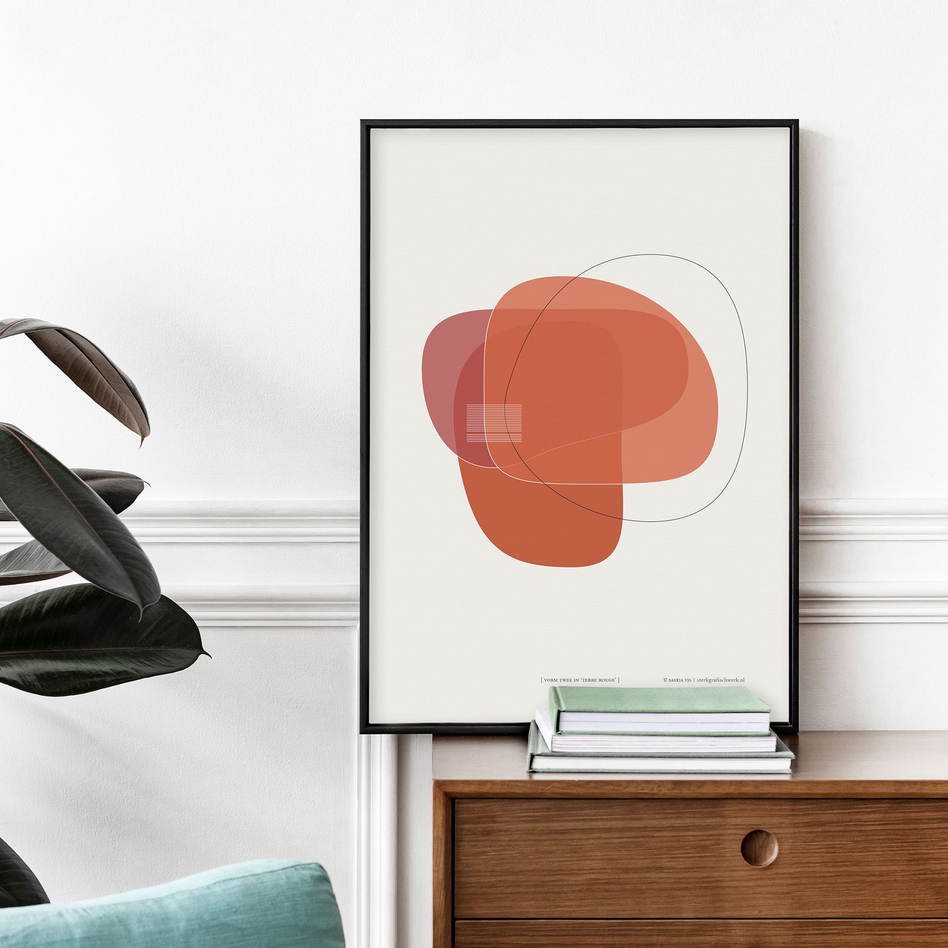 Productafbeelding poster "vorm twee in terre rouge" staande op een wandmeubel tegen een decoratieve wand ingelijst in een zwart frame
