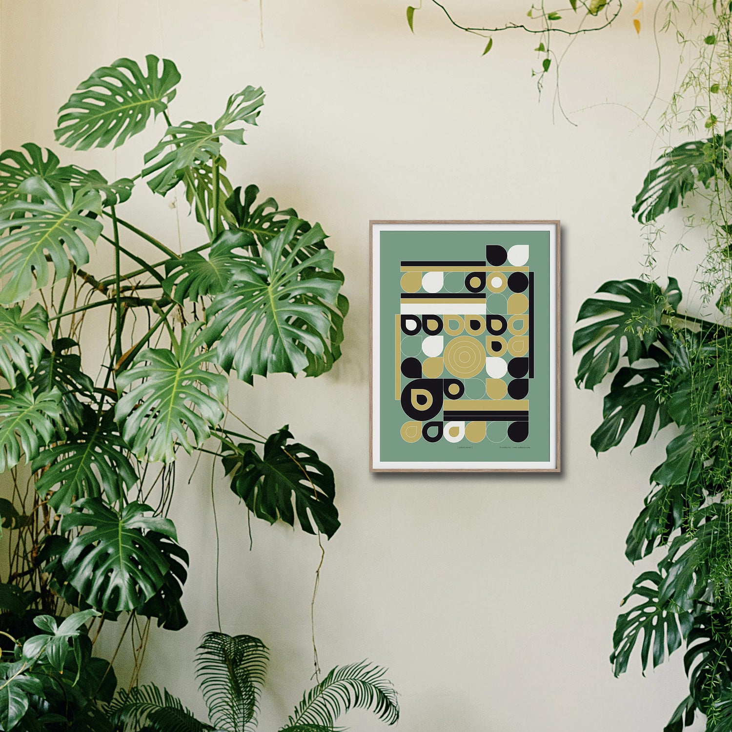 Een ingelijste poster "Jardin Jaune" aan een wand omringd met mooie groene planten, een sfeerfoto