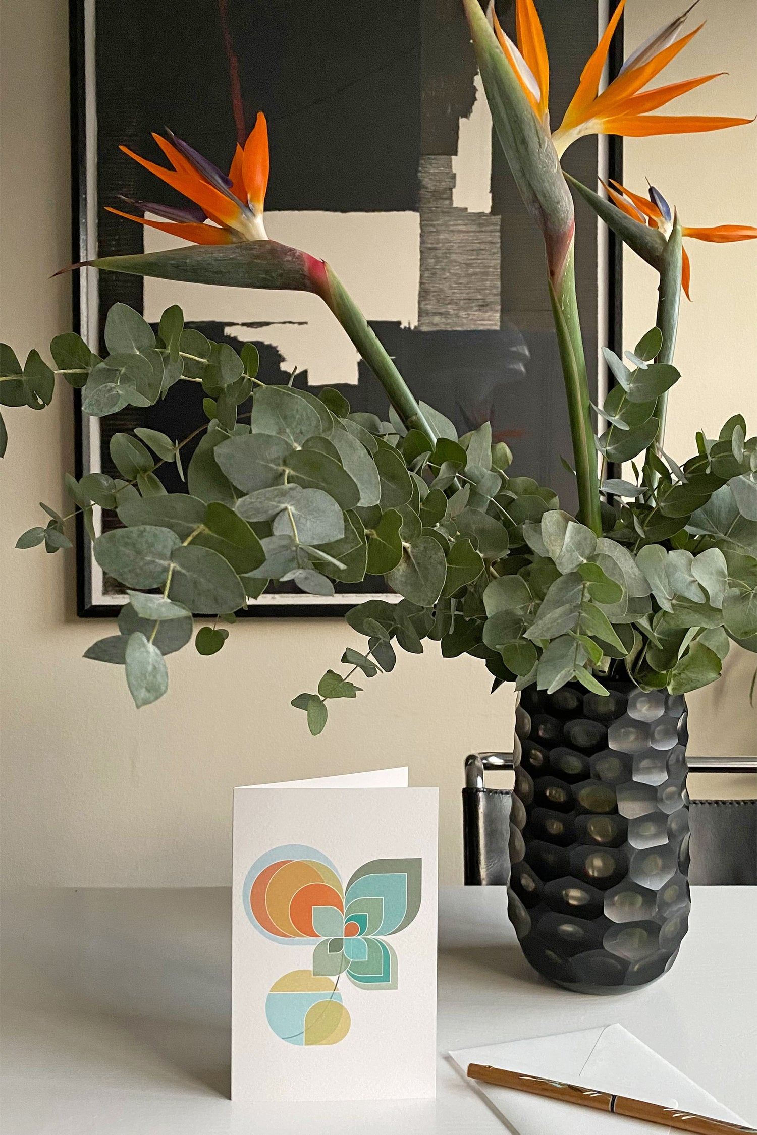 Sfeerfoto wenskaart "Vaasje Bloemen 2" op een tafel met vaas bloemen en een schilderij op de achtergrond