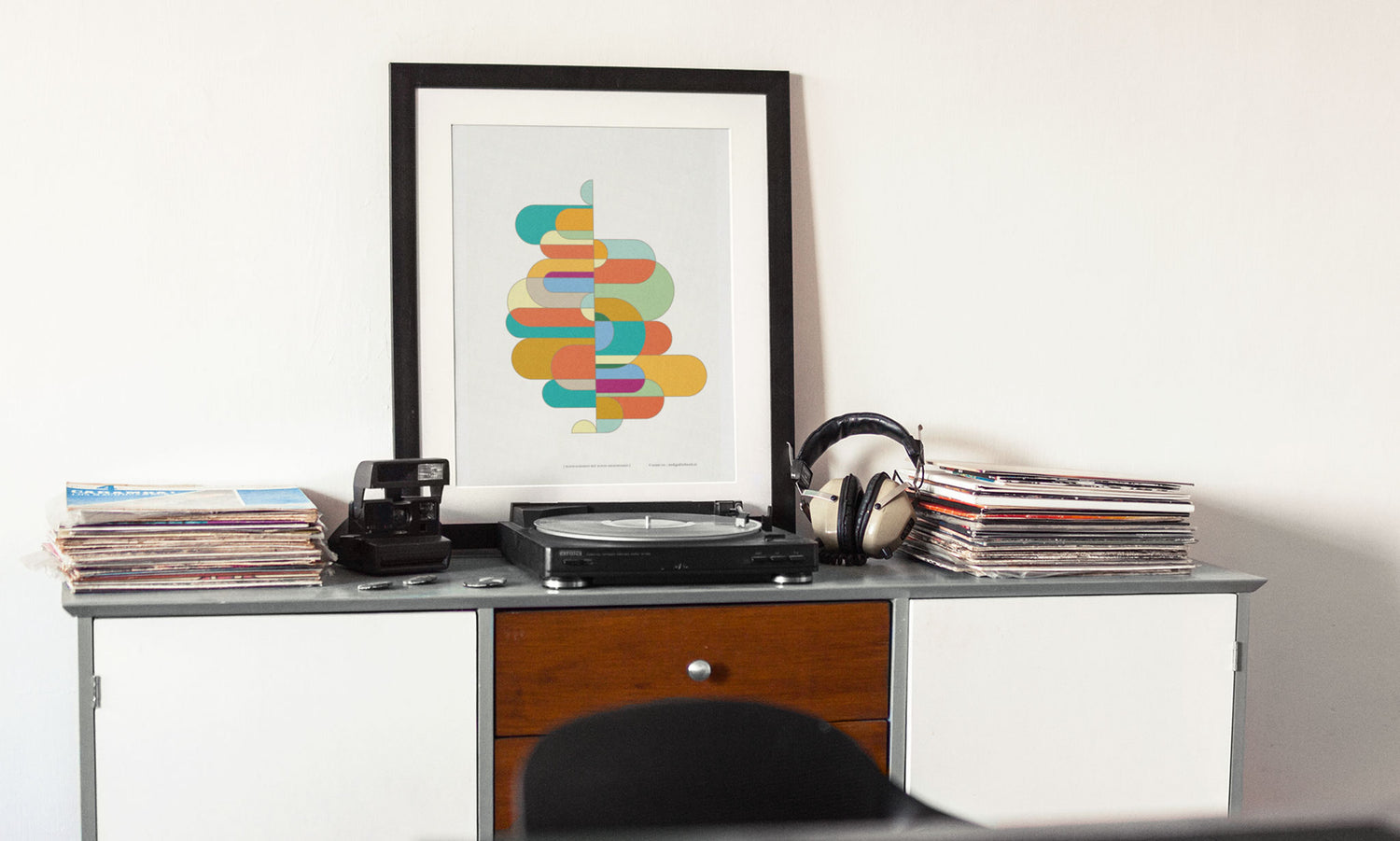 Poster "kleur-acrobaat met ronde rechthoeken" ingelijst staande op een tafel met een platenspeler in een interier