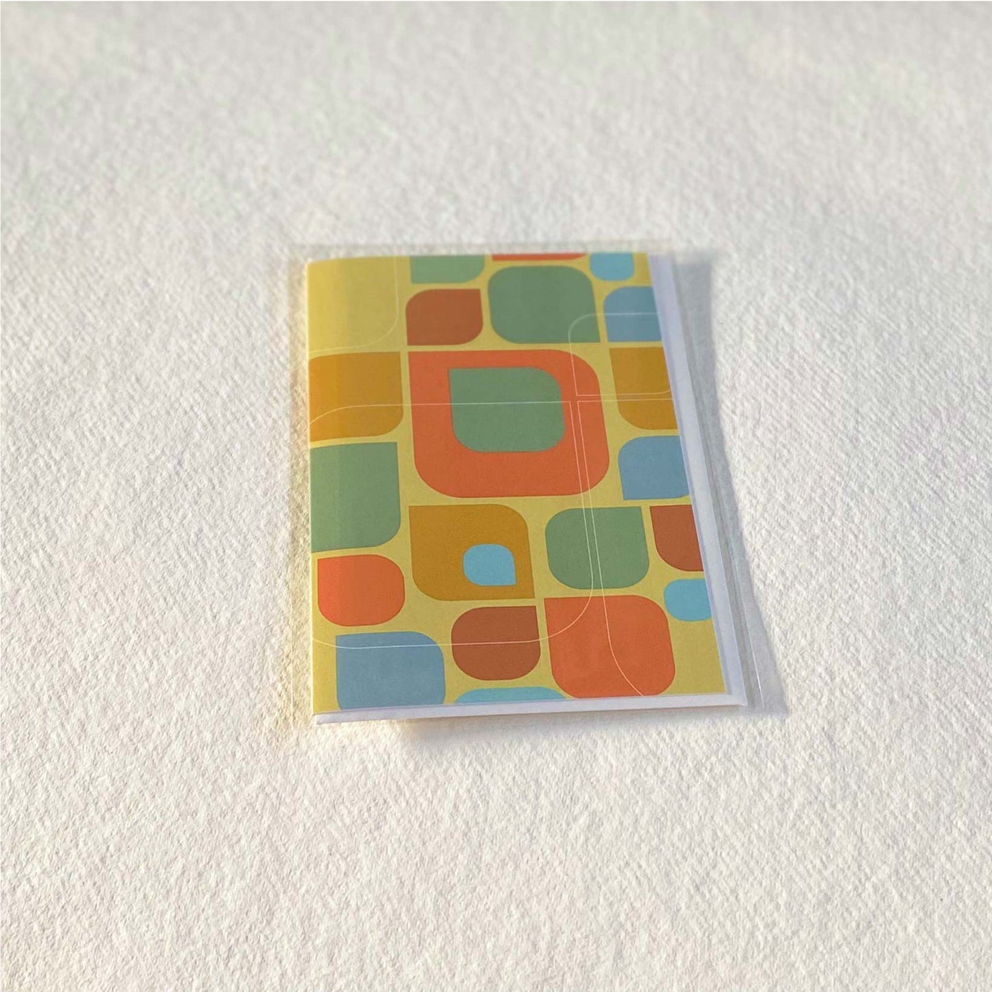 Productafbeelding, foto wenskaart "kleurmotief op oker" in zijn verpakking liggend op een achtergrond