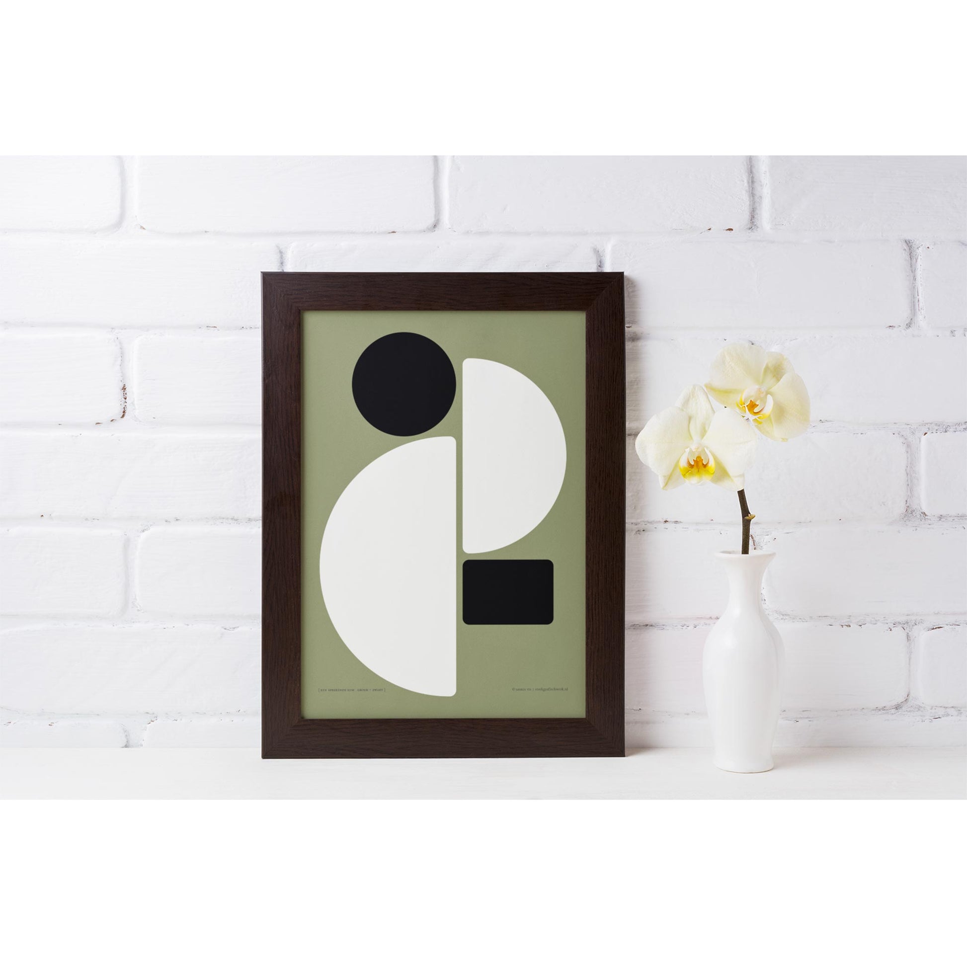 Productafbeelding poster "een sprekende som groen+zwart" 3de impressie ingelijst staand op een plank tegen een wand